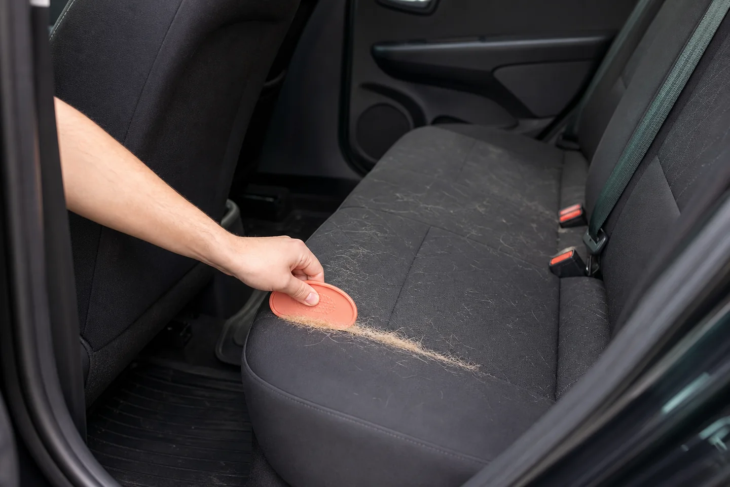 Rastrillo de goma agrupando pelo de mascota en un asiento de coche
